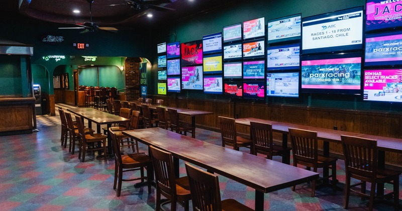 Interior, seating area with a long tables and a lot of TV screens on the wall