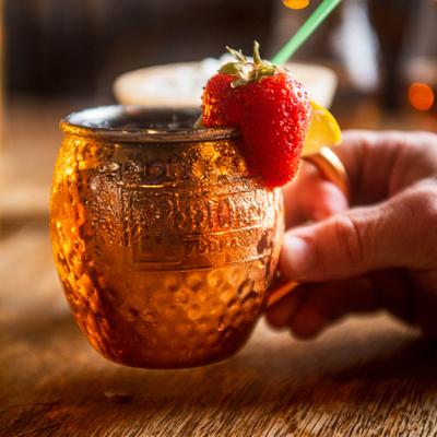 Hand holding a Strawberry Moscow Mule cocktail.