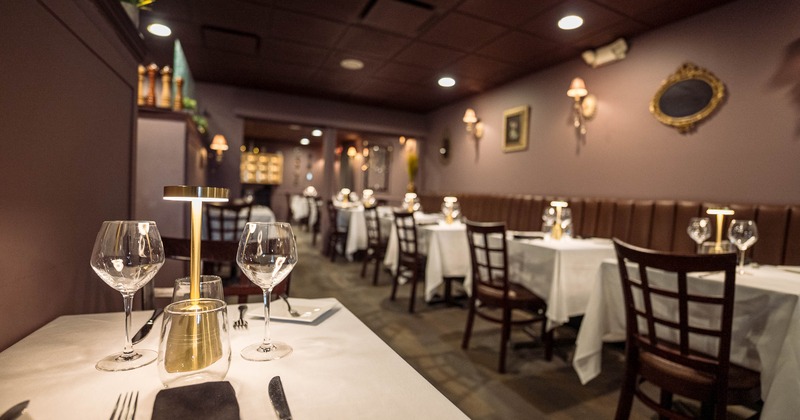 Elegant restaurant dining area with tables set with wine glasses and golden lamps.