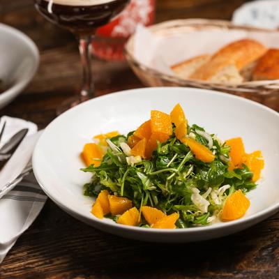 A salad with frisee lettuce, fennel, and orange slices.