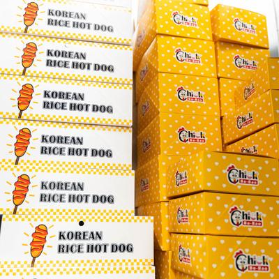 Stacks of yellow and white takeout boxes for Chick Bo-Bao Korean hot dogs.