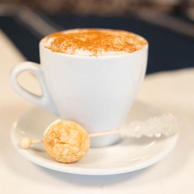 Cappuccino served with a rock candy stick and dusting of cinnamon.