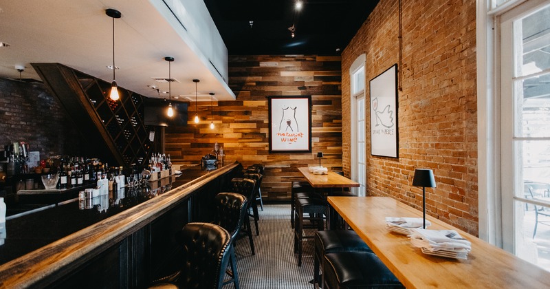 Modern and cozy restaurant interior with two long high tables and stools near the bar