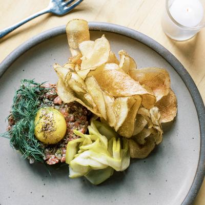 Steak Tartare appetizer with pickled cucumbers, potato chips, and dill. At Table Asheville..