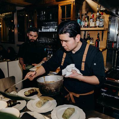 Chef pouring sauce over dishes.