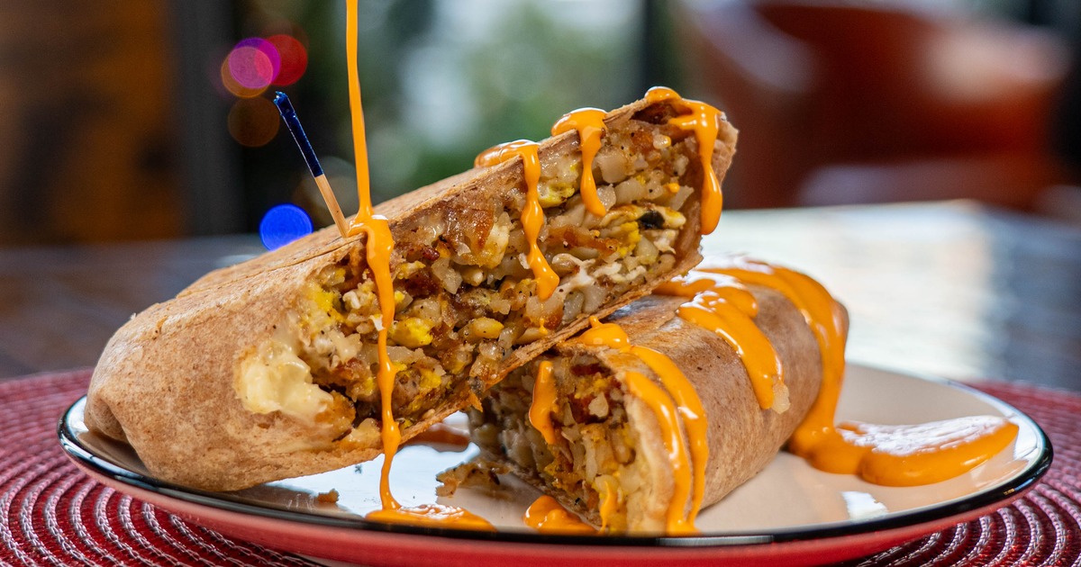 Wrap on the plate being drizzled with cheese sauce