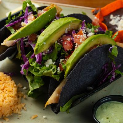 Fish tacos with avocado, purple cabbage, and fresh cheese served with rice and dipping sauce.