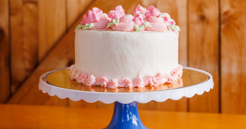 A round cake iced with white and pink frosting