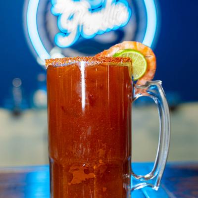 Michelada drink garnished with a shrimp and a lime slice.