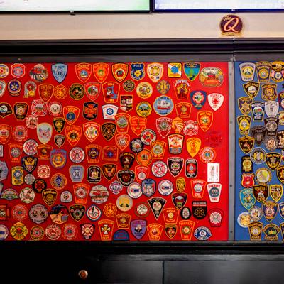 Colorful fire department and emergency service uniform patches mounted on a red background.
