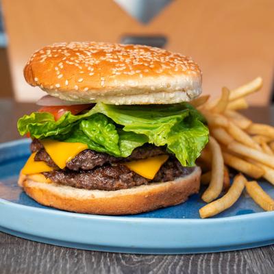 Double cheeseburger served on a blue plate with French fries.