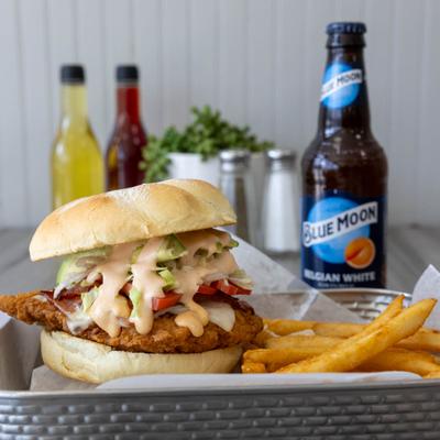 Crispy chicken sandwich with chipotle mayo and lettuce served with fries and a beer.