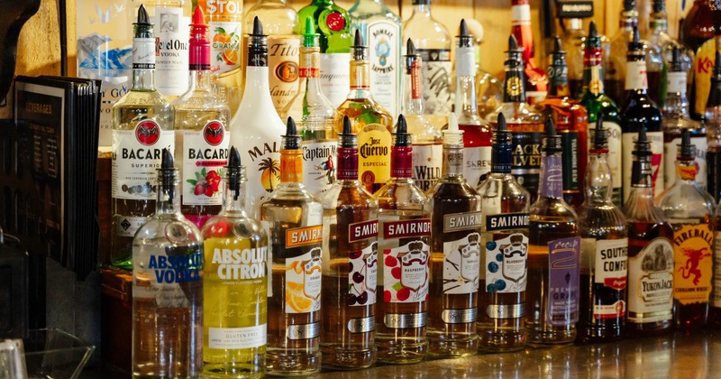Large selection of alcoholic beverages displayed on a bar shelf