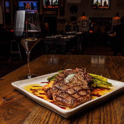 Grilled steak with asparagus served with red wine on a table.