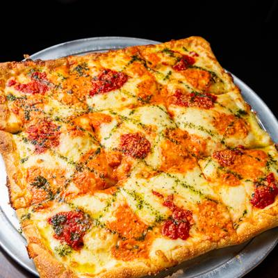 Grandma style pizza with tomato sauce, cheese and drizzle od pesto.