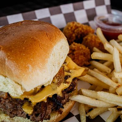 Cheeseburger with fries and fried rice balls on checkered paper.