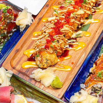 Crispy sushi roll drizzled with sauces, garnished with roe, wasabi, and pickled ginger.