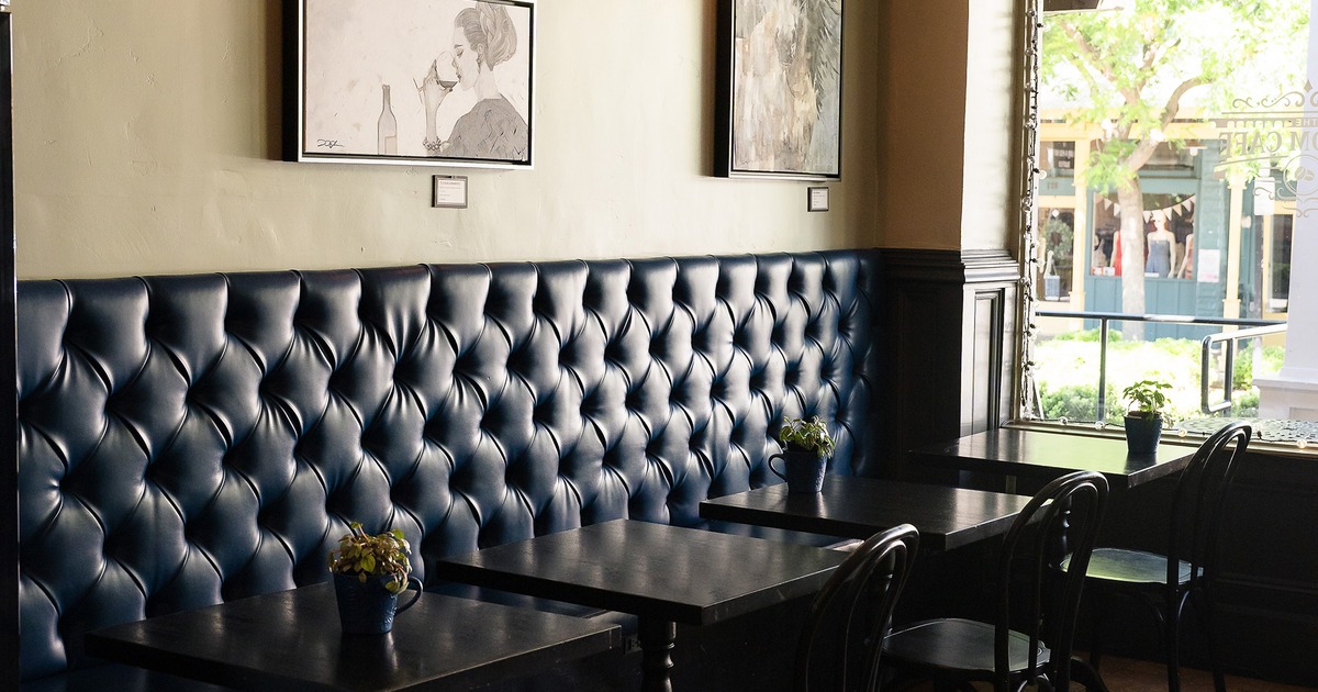 Rustic and cozy interior space, lined up tables and chairs, and upholstered seats along the wall