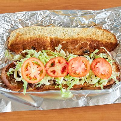 Steak hoagie with lettuce and tomato.