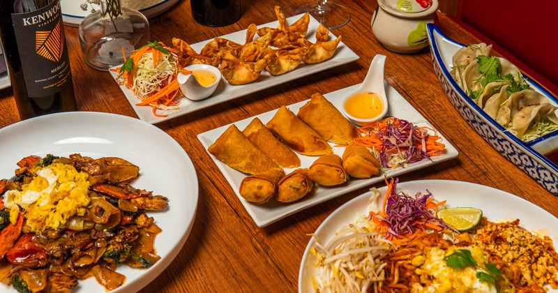 Table spread featuring steamed dumplings, spring rolls, wontons and red wine