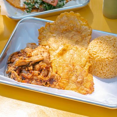 Marinated chicken, with rice, and crispy fried plantains.