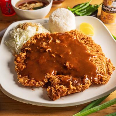 Korean-style fried pork cutlet covered in brown sauce, served with rice and cabbage.