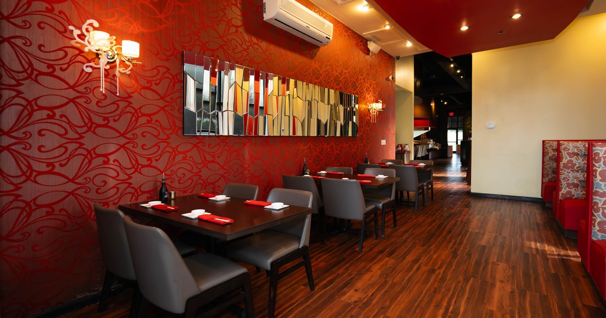 Modern restaurant interior with red patterned walls, wooden tables and chairs, and decorative mirrors