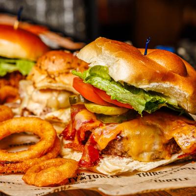 Bacon Cheddar Burger served with onion rings and other burgers.