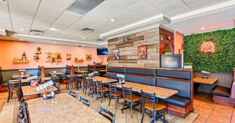 Interior of a brightly decorated Mexican restaurant with tables, booths, framed artwork