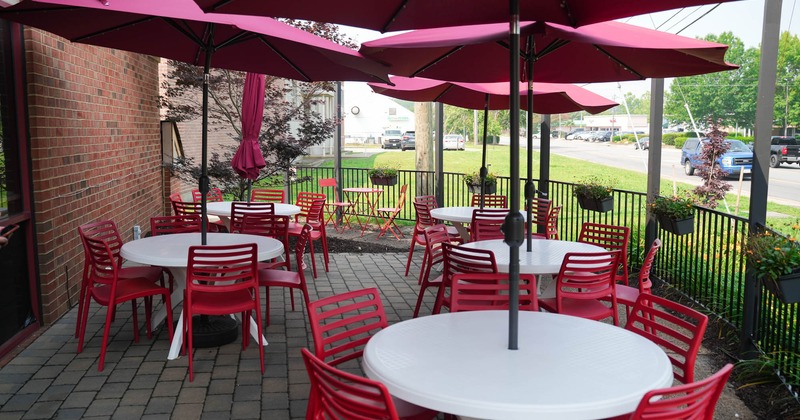 Outside, seating area with red chairs and white tables