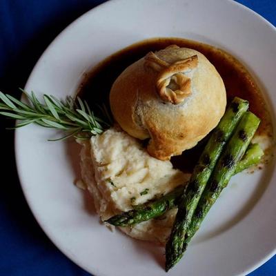 Beef Wellington with mashed potatoes, asparagus, rosemary sprig garnish, top view.
