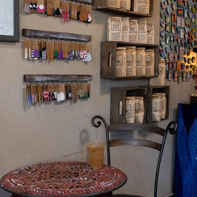 Santos Coffee House interior, coffee cup on a table by a wall with merchandise items.