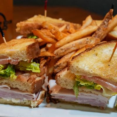 Club Sandwich served with a side of fries, close-up.
