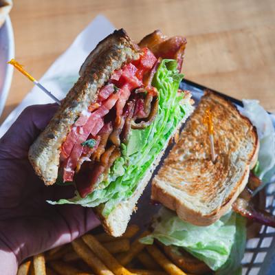 Stacked deli sandwich held above crispy fries.