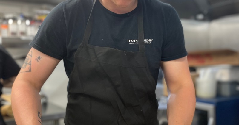 Kitchen staffer preparing catering trays with mac and cheese