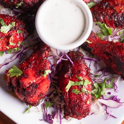 Tandoori wings served with a dip, close-up.