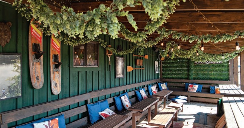 Outdoor seating featuring dark green wooden walls adorned with vintage-style oars