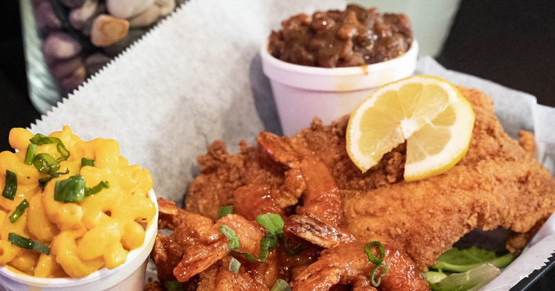 A basket with fried seafood, baked beans, mac and cheese