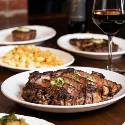 Bone-in prime ribeye with a galss of red vine.