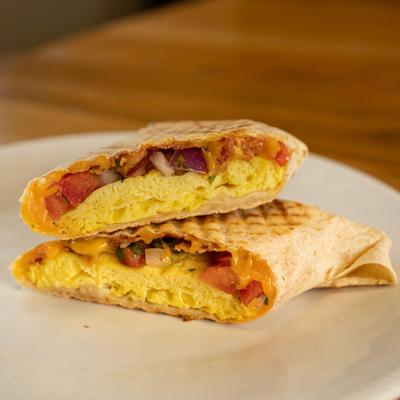 A breakfast burrito on a white plate.