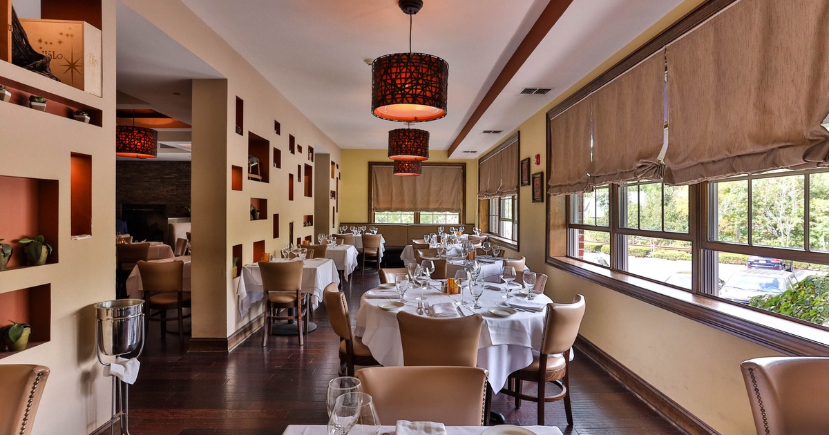 Elegant interior with tables, beige chairs and patterned pendant lights.