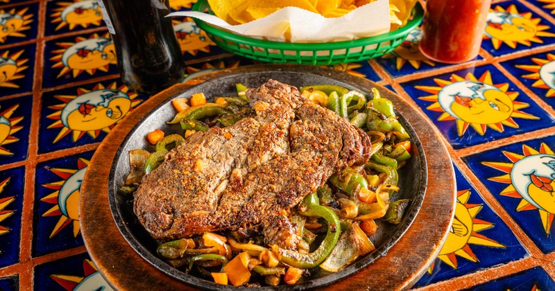 Ribeye Mexicana beside a basket of chips and a bottle of soft drink
