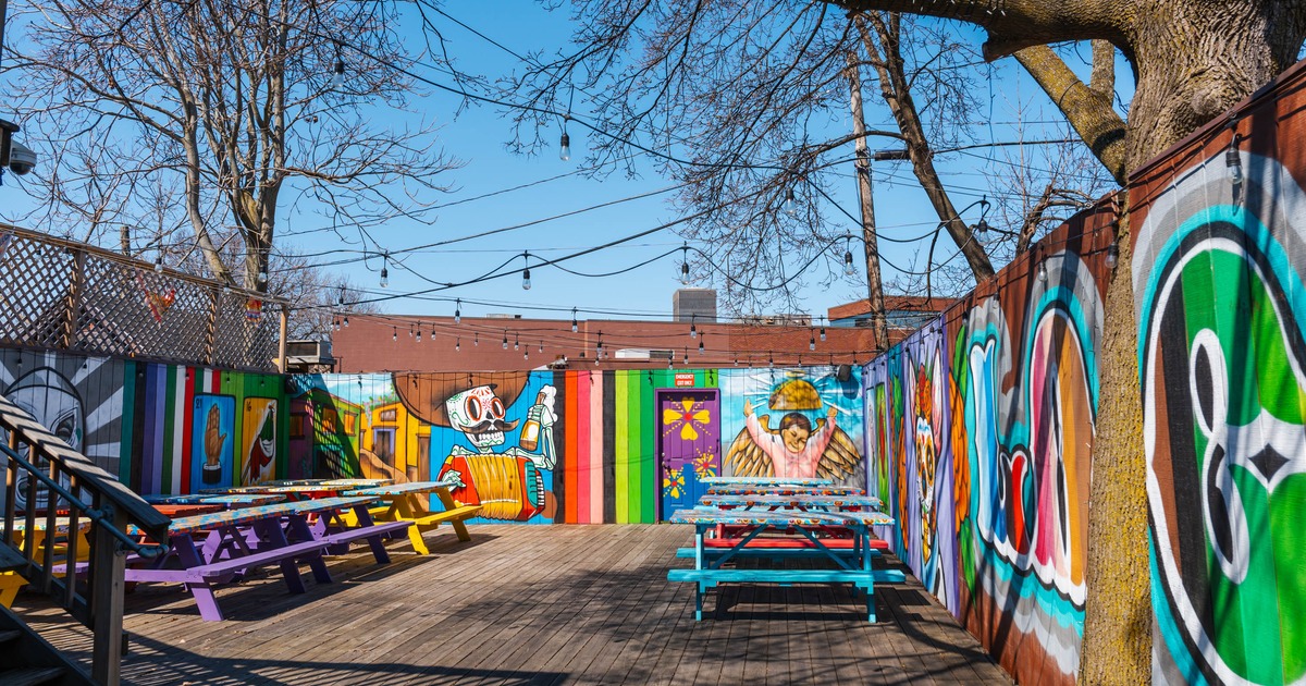 Brightly colored outdoor patio with murals and picnic tables under string lights