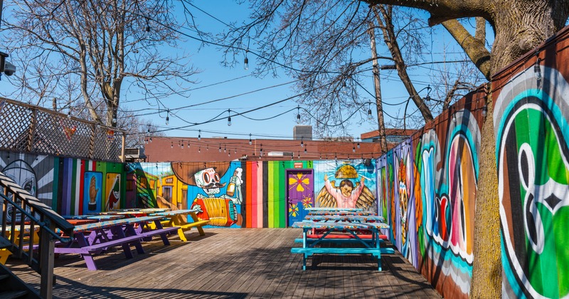 Brightly colored outdoor patio with murals and picnic tables under string lights