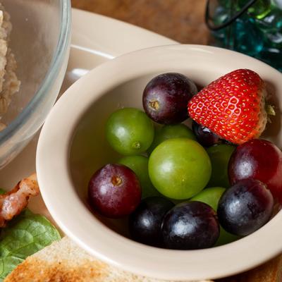 Bowl of fresh grapes and a strawberry.