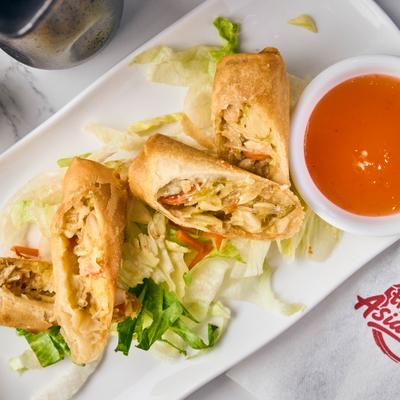 Crispy egg rolls with vegetables and dip.