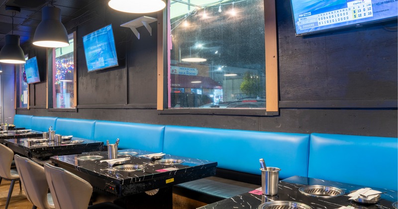 Interior of a modern restaurant with marbled tables, blue seating, and pendant lights