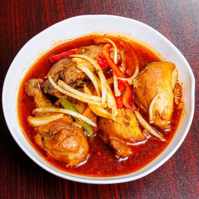 Chicken stew with peppers and onions in red sauce.