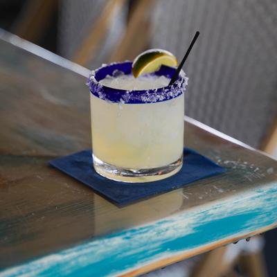 Margarita served in salt-rimmed rocks glass, garnished with a lime wedge.