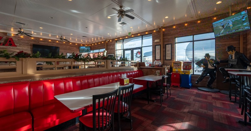 Interior, dining area, long red leather padded banquette bench with tables and chairs